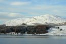 Looking across Clatteringshaws Loch to a snowy Craignell in the Galloway Forest Park