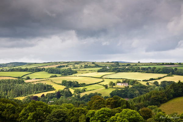 Sunlit Restormel Castle under stormy skies